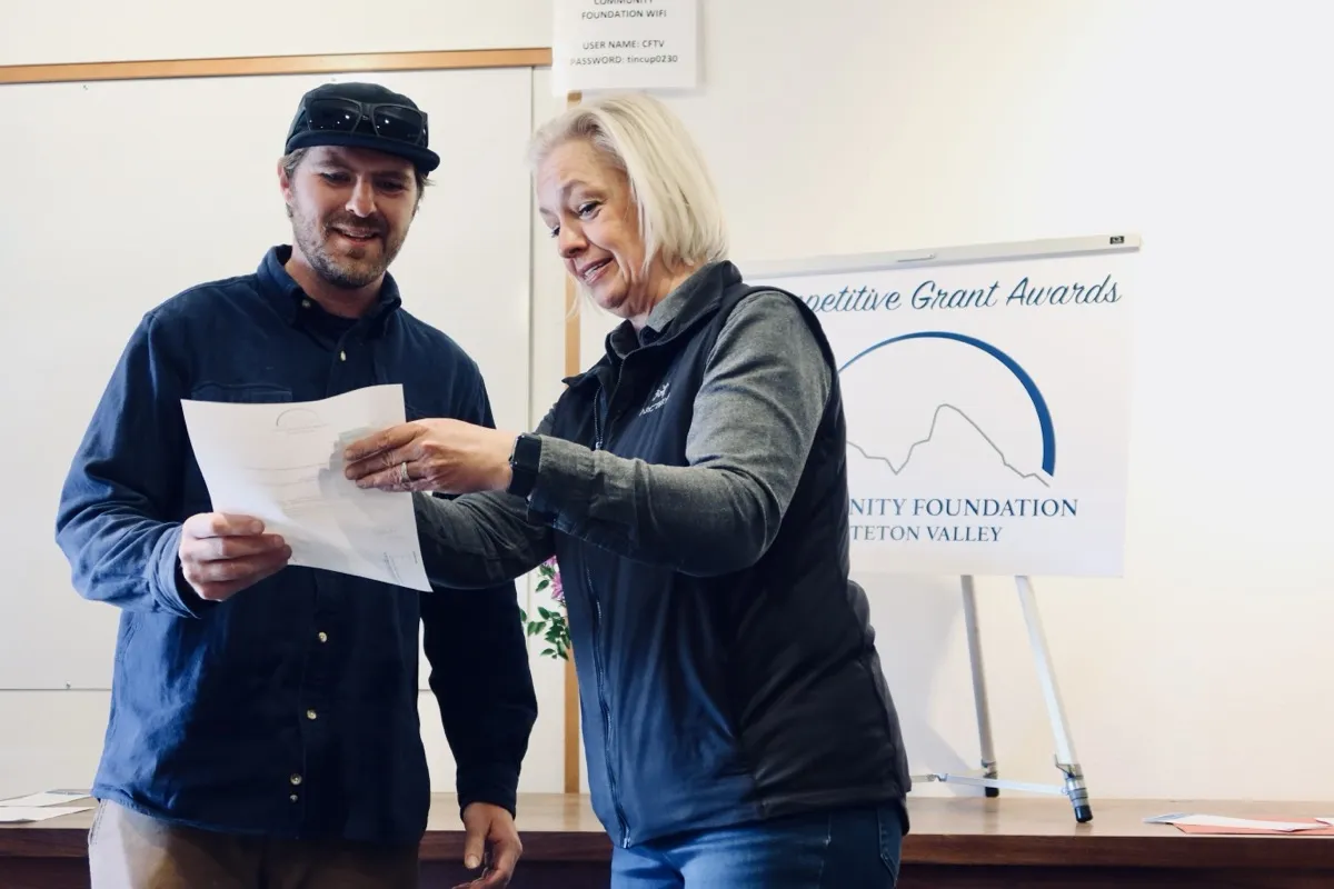 Two people reading a competitive grant award letter at the Community Foundation ceremony
